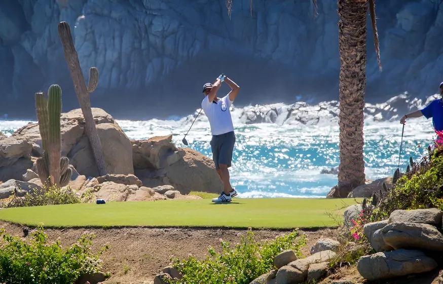 Golfer teeing off beside the ocean in Los Cabos
